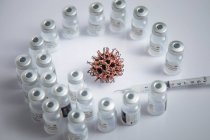 Microscopic Simulation Of COVID-19 Virus Pattern In Background Surrounded By Vaccine Vials — Stock Photo