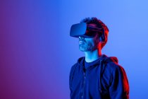 Unrecognizable bearded male in headset exploring virtual reality in neon light — Stock Photo