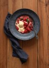 Vista superior de sabrosas mitades de fresa flambeed con helado de vainilla en plato sobre mesa de madera - foto de stock