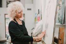 Жінка-художник створює малюнок людини з олівцем, стоячи на мольберті в студії — стокове фото