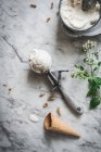 Desde arriba de cono de gofre cerca de merengue cucharadas de helado de leche y hojas de menta fresca en la mesa de mármol - foto de stock