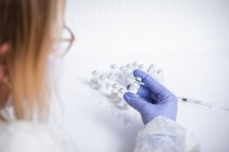 Руки неузнаваемой женщины-врача с пузырьком коронавируса — стоковое фото