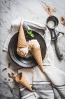 De cima de cones de waffle com gotas de gelato de leite merengue e folhas de hortelã frescas com pó de canela em cima — Fotografia de Stock