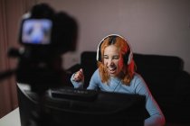 Smiling female gamer in headphones recording video on professional camera for social media blog — Stock Photo