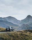 Auto moderna guida su un sentiero polveroso tra le verdi montagne dei Pirenei con foresta in Spagna — Foto stock