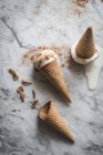 Vue aérienne de savoureux cônes de gaufres avec des cuillères de lait glacé meringue crémeuse sur table en marbre — Photo de stock