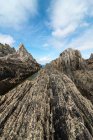 Живописный вид скалистых образований на пляже Гайруа возле спокойного моря под голубым небом в Астурии — стоковое фото