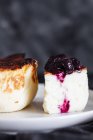 Deliciosas fatias de cheesecake cozido no forno coberto com geléia de baga servida em uma placa no fundo preto — Fotografia de Stock