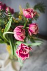 Квітучі рожеві квіти з ніжними пелюстками та зеленим листям у вазі на сірому фоні — стокове фото