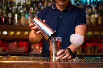 Mãos de barman irreconhecível segurando uma coqueteleira para misturar um coquetel no bar — Fotografia de Stock