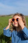 Зверху дівчина в модному одязі і сонцезахисних окулярах тримає руки за голову і розслабляється на трав'яному газоні — стокове фото