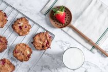 Vista superior de biscoitos caseiros saborosos com morangos colocados na mesa com copo de leite fresco — Fotografia de Stock