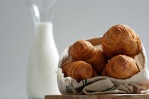 Délicieux croissants et bouteille de lait mis sur la table pour le petit déjeuner dans la cuisine — Photo de stock