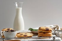 Leckere hausgemachte süße Kekse mit Schokoladenschiffen auf Tablett mit Glas Milch serviert — Stockfoto
