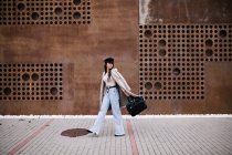 Вид збоку на жінку-підприємця в стильному одязі і з сумочкою, що йде вулицею в місті і дивиться в сторону — стокове фото
