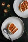 Vue de dessus du délicieux gâteau au fromage à la crème servi dans des assiettes avec des tranches de carotte fraîche et des noix — Photo de stock