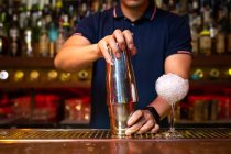Mãos de barman irreconhecível segurando uma coqueteleira para misturar um coquetel no bar — Fotografia de Stock