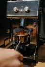 Растениеводство неузнаваемый бариста с помощью кофемолки при приготовлении ароматного свежего кофе в кафе в дневное время — стоковое фото