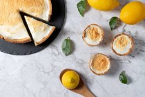 From above of sweet meringue pie and fresh lemons arranged on marble table in kitchen — Stock Photo