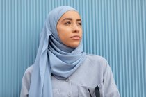 Jovem muçulmana solitária com olhar melancólico olhando para a parede nervurada durante o dia — Fotografia de Stock
