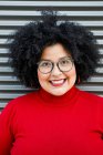 Mujer adulta con sobrepeso en ropa brillante y gafas con peinado afro mirando a la cámara - foto de stock