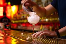 Hände des nicht wiederzuerkennenden Barkeepers, der zerstoßenes Eis in die Tasse füllt, während er in der Bar einen Cocktail zubereitet — Stockfoto