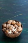 Bol rond en bois plein de noix croquantes avec des noix sèches inégales sur la table — Photo de stock