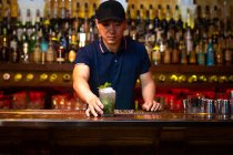 Young Asian bartender gives you a grapefruit juice gin cocktail in the bar after he finished to prepare it — Stock Photo