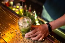Unbekannter Barkeeper hält das Glas und rührt Mojito-Cocktail in der Bar — Stockfoto