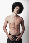 Jeune homme noir confiant avec six pack abs et coiffure afro regardant la caméra sur fond blanc — Photo de stock