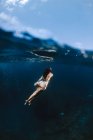 Touriste féminine en maillot de bain nageant dans une mer transparente propre pendant les vacances dans une station balnéaire tropicale ensoleillée — Photo de stock
