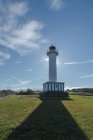 Shadow leading to white lighthouse placed in Faro de Lastres in Asturias in Spain under cloudless blue sky in daytime — Stock Photo