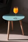 From above of glass of fresh orange juice placed on small round table near comfortable sofa in sunlight — Stock Photo