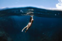 Жінка-туристка в купальнику плаває в чистому прозорому морі під час відпустки в сонячному тропічному курорті — стокове фото