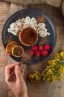 De cima da colheita cozinheiro anônimo com prato de flan cozido gostoso com framboesas maduras e canela em pó — Fotografia de Stock