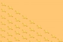 D'en haut de composition de nombreux petits avions jaunes placés sur fond jaune en studio — Photo de stock