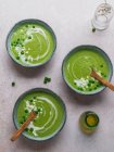Top view of delicious pea cream soup in bowls served on table with vase with flowers — Stock Photo
