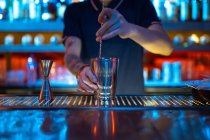 Hände eines unkenntlichen Barkeepers bei der Arbeit, der in der Bar in seinem Shaker einen Cocktail rührt — Stockfoto