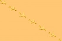 De cima da composição de muitos pequenos aviões amarelos colocados contra o fundo amarelo no estúdio — Fotografia de Stock