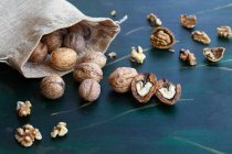 From above bag with whole and halved walnuts with dry nutshells and heart shaped center on table — Stock Photo