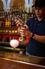 Barman travaillant avec shaker pour mélanger un cocktail dans le bar — Photo de stock