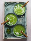 Vista dall'alto di deliziosa zuppa di crema di piselli in ciotole servita sul tavolo con tovagliolo e vaso con fiori — Foto stock