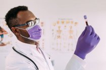 Medico afroamericano di sesso maschile in guanto medico che dimostra la provetta con campione di sangue su sfondo bianco — Foto stock