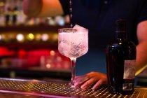 Young Asian bartender pouring tonic water to the glass for preparing a gin tonic cocktail in the bar — Stock Photo