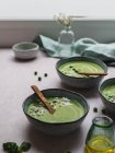 From above of delicious pea cream soup in bowls served on table with napkin and vase with flowers — Stock Photo