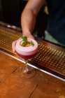 Mains de barman méconnaissable servant un cocktail avec des feuilles de menthe et des fruits de la passion dans le bar — Photo de stock