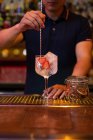 Невпізнаваний бармен, який перемішує джинсовий тонізуючий коктейль з ложкою в барі — стокове фото