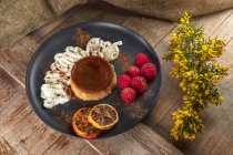 Dall'alto di flan saporito con panna montata e fette arancioni rosse con polvere di cannella su piatto di ceramica — Foto stock
