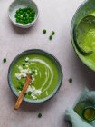 Top view of delicious pea cream soup in bowls served on table with napkin and vase with oil — Stock Photo