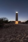 Faro con luci luminose posto sulla spiaggia sabbiosa di Faro de Trafalgar a Cadice in Spagna sotto il cielo notturno con stelle — Foto stock